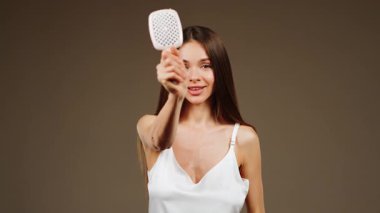 Manken, saç şekillendirme tekniklerini sağlıklı ve parlak saçlar için bir fırçayla gösterir.