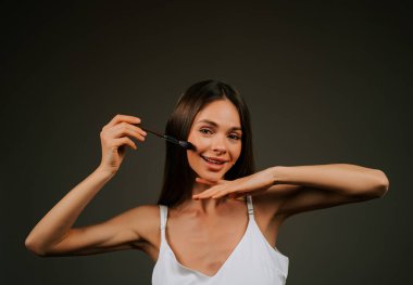 Gündüz vakti güzellik stüdyosunda fırçayla makyaj yapan bir kadın.