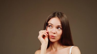 Evde rahat bir ortamda makyaj fırçası uygulama tekniklerini gösteren bir kadın