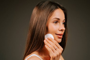 Kadın, akşam rutininde makyajını temizlerken pamukla cildini temizliyor.