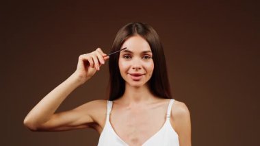 Kadın sakin bir ortamda kaşlarını titizlikle fırçalar.