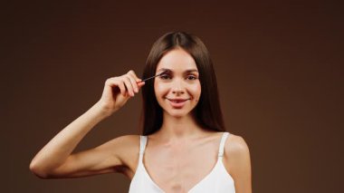 Tarafsız bir ortamda kaşlarını tarayan bir kadın.