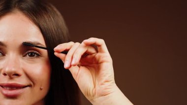 Kadın kaşlarını bir fırçayla şekillendiriyor.