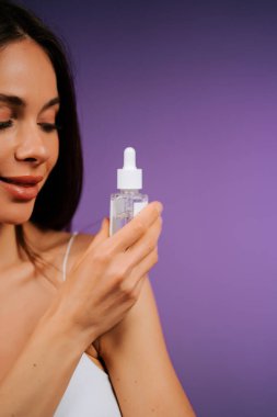 Cilt rutini için pipet kullanarak yüz serumu uygulayan bir kadın.