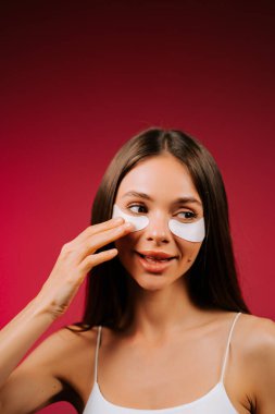 Stüdyodaki genç bir kadının taze cildine kolajen pedlerle güzellik tedavisi