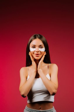 Göz bandı takmış güzel bir kadın stüdyo çekiminde taze cilt için kolajen pedleri uyguluyor.