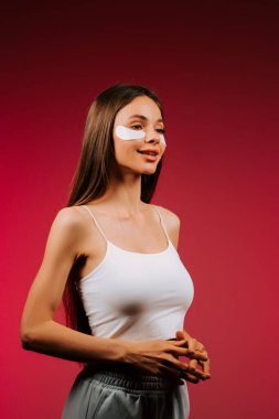 Göz bandı takmış güzel bir kadın stüdyo ortamında temiz cilt için kolajen pedleri kullanıyor.