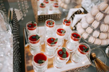 Zarif bir açık büfede kırmızı jöle bardakları ve kurabiyeler içeren lezzetli bir tatlı sergisi.