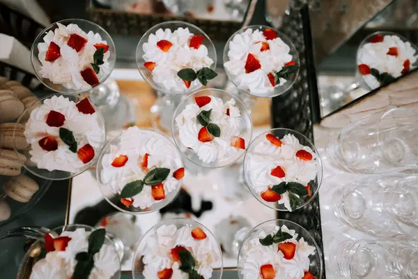 Şenlikli bir toplantıda krema ve taze çilekle kaplı lezzetli tatlı fincanları.