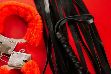 BDSM aksesuarları, doku ve renk odaklı canlı kırmızı bir arkaplanda görüntülenir
