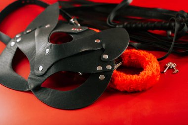 BDSM ekipmanları, bir maske ve bağlama, canlı kırmızı bir arka plan karşı duruyor