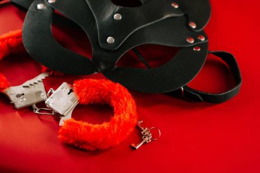 Erotik keşif ve oyun için canlı kırmızı bir arkaplan üzerine dizilmiş BDSM oyuncakları