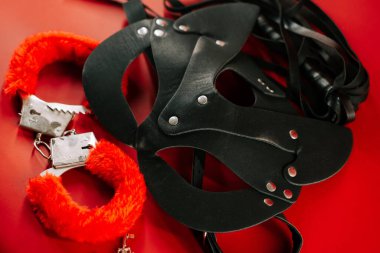 BDSM oyuncakları samimi bir keşif oturumu sırasında canlı kırmızı bir arkaplanda gösterilir