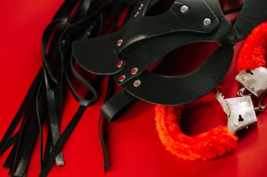 Yakın keşif için canlı kırmızı arkaplanda BDSM aksesuarları görüntülendi