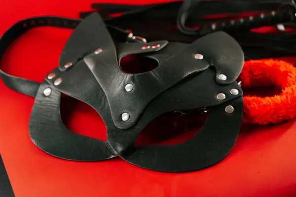 BDSM ekipmanları çeşitli oyuncak ve aksesuarların yer aldığı canlı kırmızı bir arkaplanda sergilenmektedir