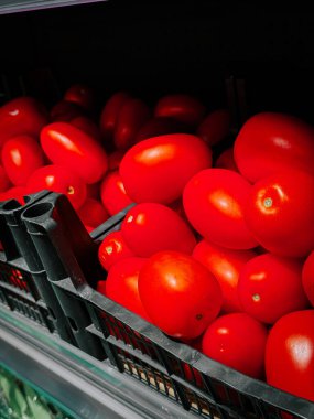 Güneşli bir öğleden sonra manavda sergilenen taze kırmızı domatesler.