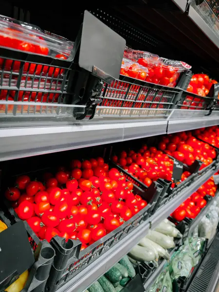 Parlak ışıkta bir markette raflarda sergilenen taze kırmızı domatesler.