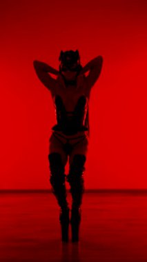 Kedi kostümlü kadın dansçı çarpıcı kırmızı neon ışığın altında gösteri yapıyor.