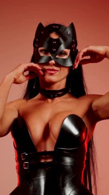 Kedi kostümlü kadın dansçı kırmızı ışıkların altında zarif hareketlerini sergiliyor.