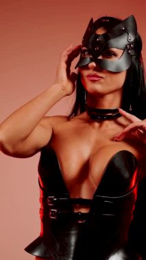 Kedi kostümlü kadın dansçı, şehir dans stüdyosunda kırmızı neon ışıkla poz veriyor.