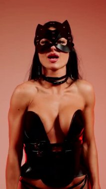 Kedi kostümlü dansçı canlı kırmızı neon ışığı altında dans eder.