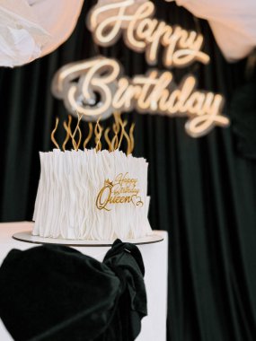 Zarif bir doğum günü pastası kutlaması. Altın aksanlı ve zarif bir ortamda kraliçe temalı.