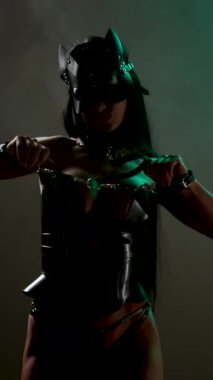 Kedi maskeli ve kelepçeli dansçı stüdyo ortamında büyüleyici pozlar veriyor.