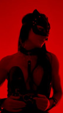 Kedi maskeli ve kelepçeli dansçı stüdyo ortamında büyüleyici bir performans sergiliyor.