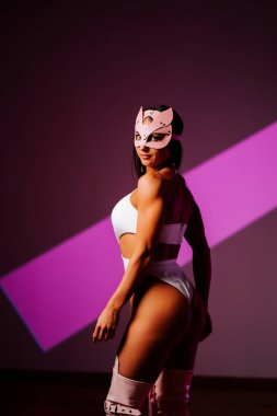 Pembe kedi maskeli kadın dansçı akşam saatlerinde dans stüdyosunda güven içinde poz veriyor.