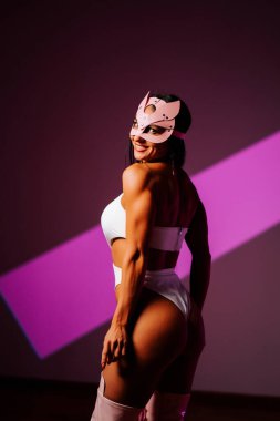 Dansçı yaratıcı bir seans sırasında pembe kedi maskesi ve şık bir kıyafet giyerek stüdyoda poz verir.
