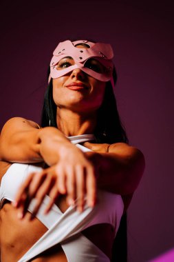 Pembe kedi maskeli kadın dansçı dans stüdyosunda zarifçe poz veriyor.