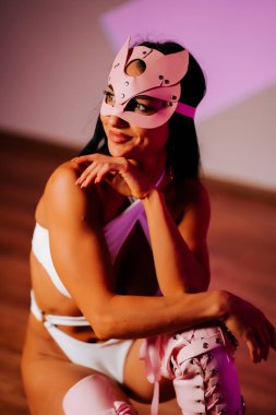 Pembe kedi maskeli kadın dansçı stüdyo ortamında zarif pozlar veriyor.