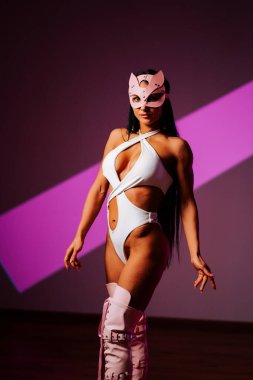 Pembe kedi maskesi takan kadın dansçı modern bir stüdyo ortamında gösteri yapıyor.