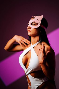 Pembe kedi maskeli kadın dansçı stüdyo ortamında zarifçe poz veriyor.