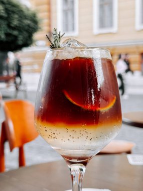 Canlı bir caddede zarif bir bardakta servis edilen limonlu ve buzlu soğuk kahveyi tazeliyorum.