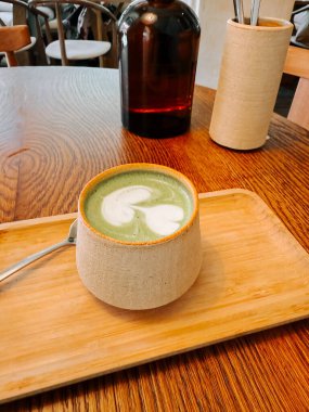 Sıcak bir kafede eşsiz bir bardakta servis edilen sıcak bir kibrit içeceğinin tadını çıkarıyorum.