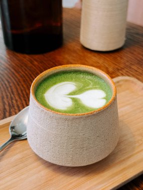 Sıcak kafe ortamında, ahşap tepside el yapımı bardakta servis edilen kibrit içeceği.