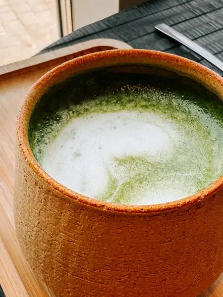 Geleneksel bir kasede sunulan kibrit içeceği güneşli bir pencerenin yanındaki ahşap tepside.