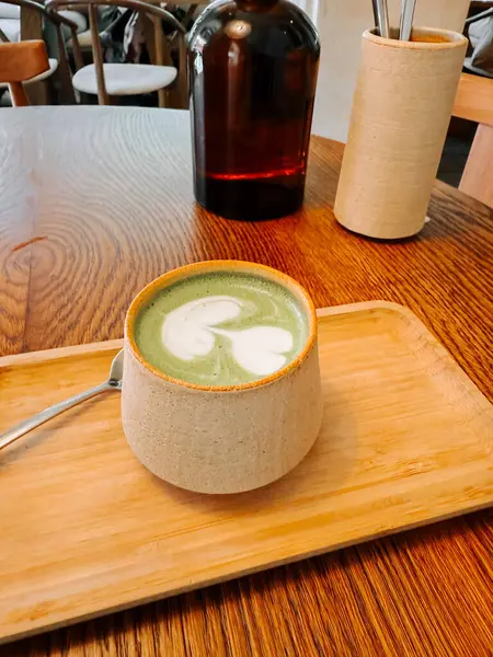 Sıcak bir kafede eşsiz bir bardakta servis edilen sıcak bir kibrit içeceğinin tadını çıkarıyorum.