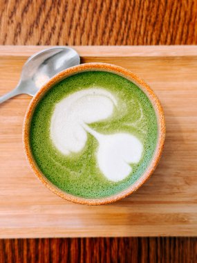 Kalp şeklinde köpük sanatı olan el yapımı kibrit içeceği, ahşap tepside oturarak keyif almaya hazır.