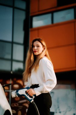 Akşam saatlerinde şehir merkezindeki şarj istasyonunda çalışan bir kadın.