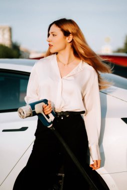 Kızıl saçlı genç kadın alışveriş merkezinde elektrikli araba şarj ediyor.