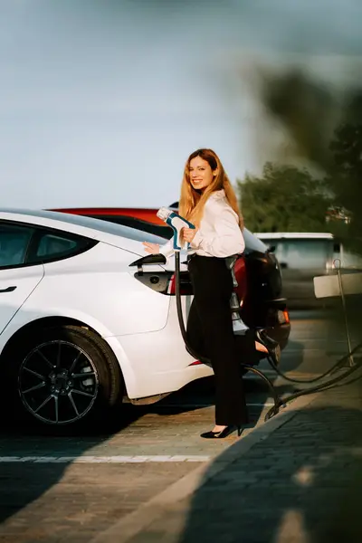 Kızıl saçlı genç bir kadın güneşli bir günde alışveriş merkezinin yakınında elektrikli araç kullanıyor.