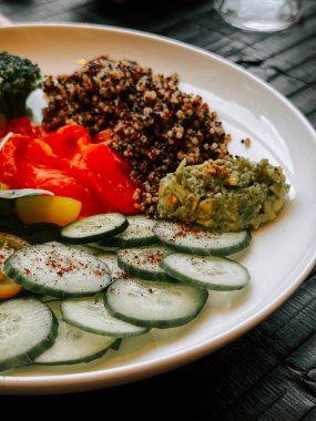 Taze kinoa salatası, sebze ve avokado sosu tabakta servis edilir.