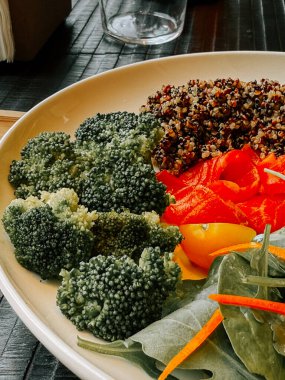 Yerel bir restoranda taze ve sağlıklı kinoa ve canlı sebzelerle servis edilen salata kasesi.