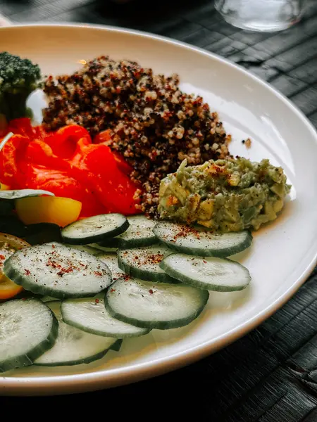 Taze kinoa salatası, sebze ve avokado sosu tabakta servis edilir.