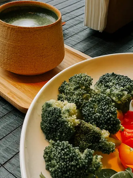 Sıcak bir lokantada, ahşap bir masada taze sebze ve bitki çayı.