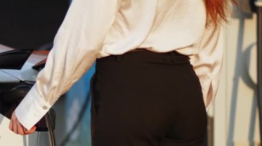 Gün batımında şehir merkezinde genç bir kadın elektrikli araçtan para alıyor.