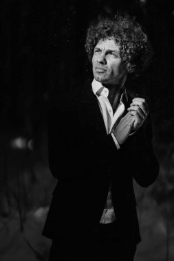 Dışarıdaki bir adamın siyah beyaz portresi, zarif giyinmiş, çevresini inceliyor.