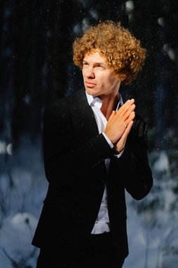 Manken, kış ormanlarıyla çevrili zarif siyah bir takım elbiseyle poz verir.